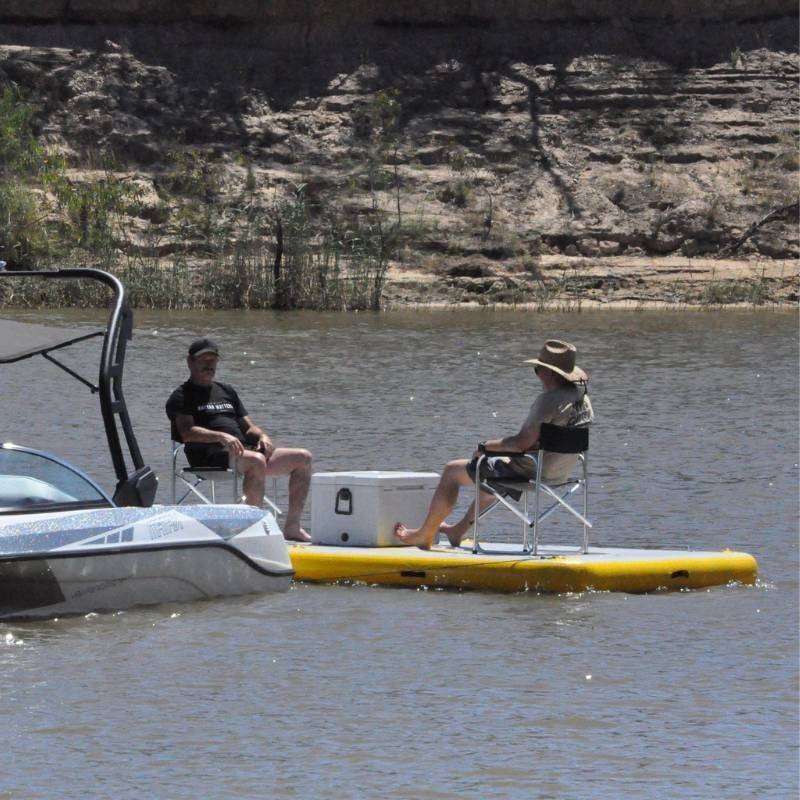 Two people sitting on Bartlett 4m X 2m deck extender inflatable pontoon with a cooler on a lake