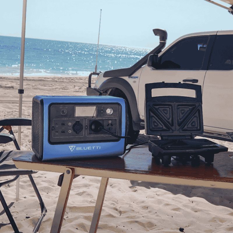 Bluetti EB70 portable power station at a beach camping setup with an eb70 bluetti powering appliances