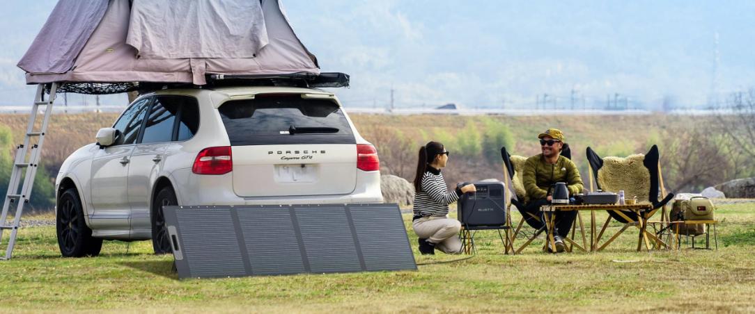 Bluetti PV200D solar panel set up next to an off-grid camping site, charging a portable power station for outdoor energy needs.