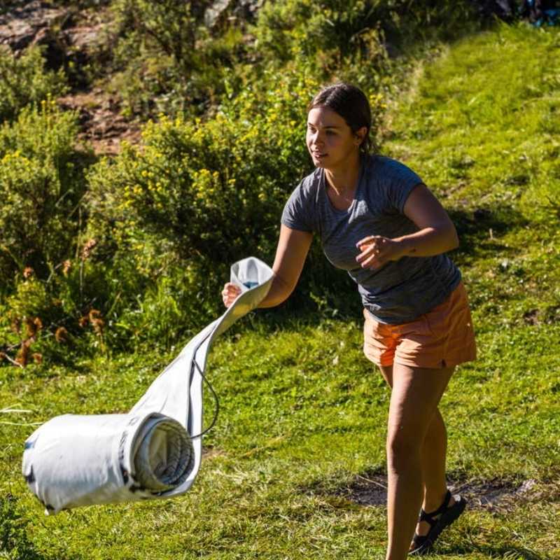 Woman unrolling Kokopelli Chasm-Lite SUP board in an outdoor setting