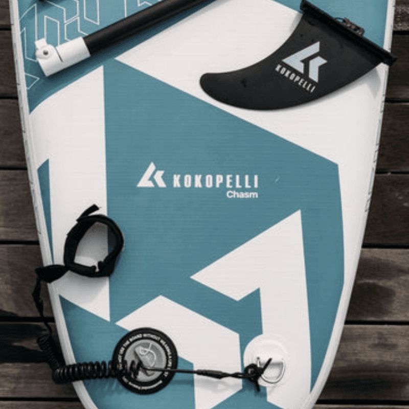 Close-up of Kokopelli Chasm-Lite SUP board showing fin, leash, and paddle