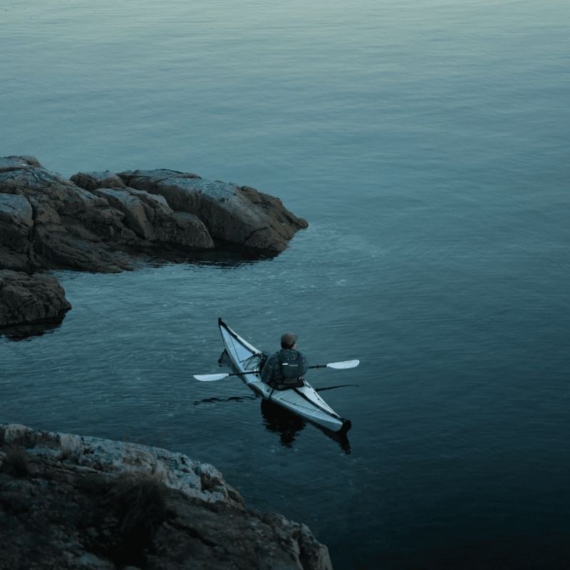 Oru Bay Folding Kayak exploring a river with surrounding rocks