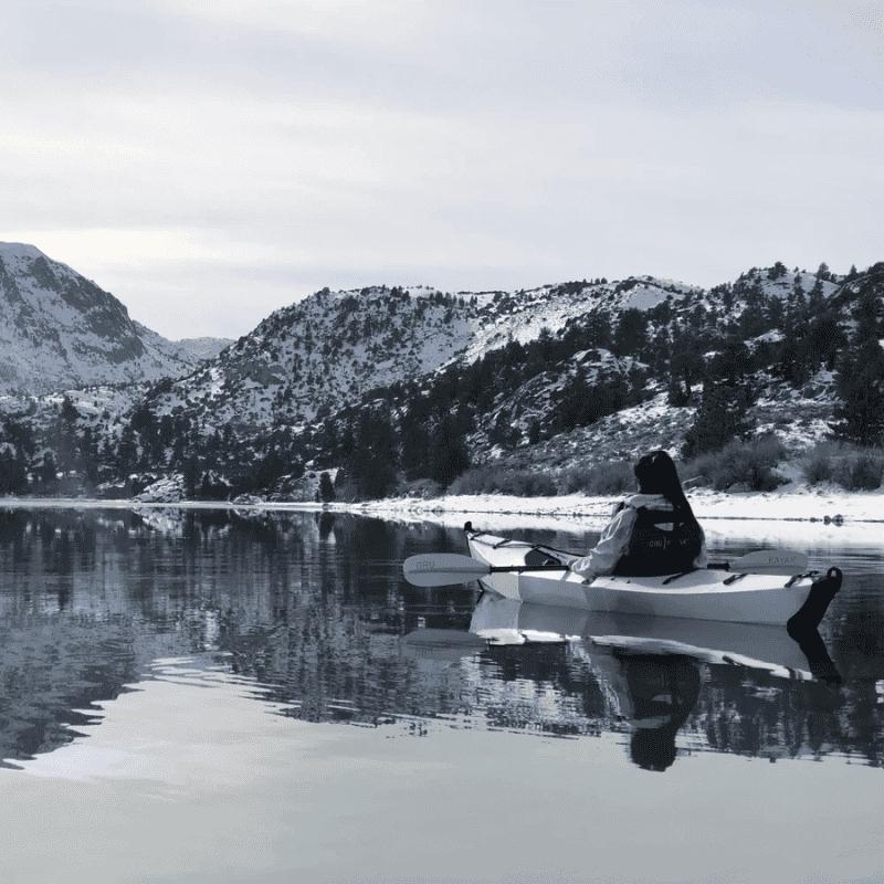 Oru Beach LT kayak paddling on a winter lake surrounded by snow