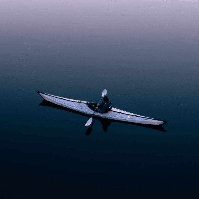 Oru Coast Xt kayak paddling on calm water at sunset