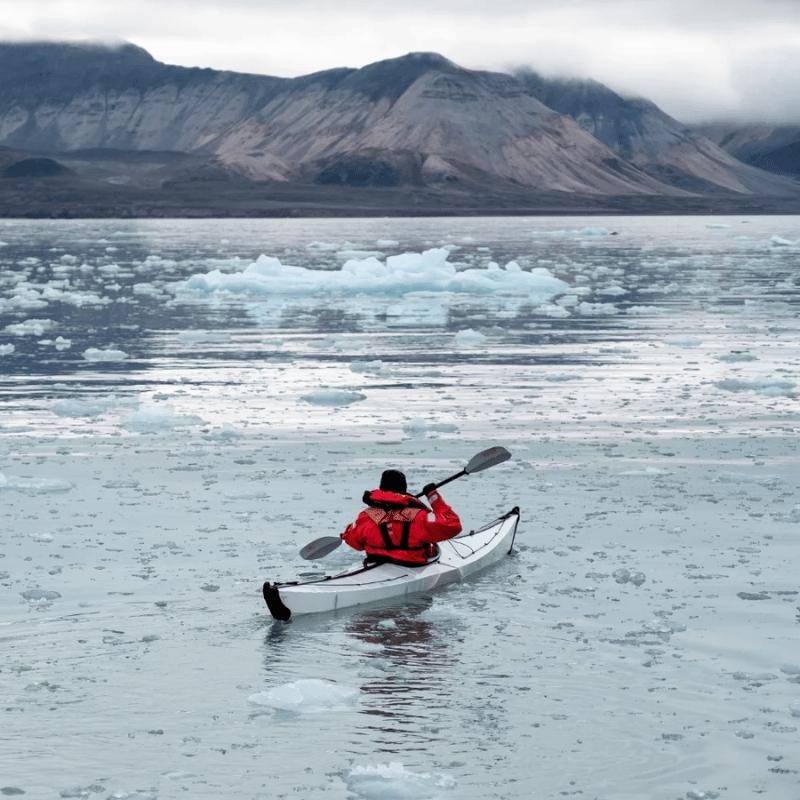 Oru Kayak Coast Xt paddling through icy waters with mountains in the background