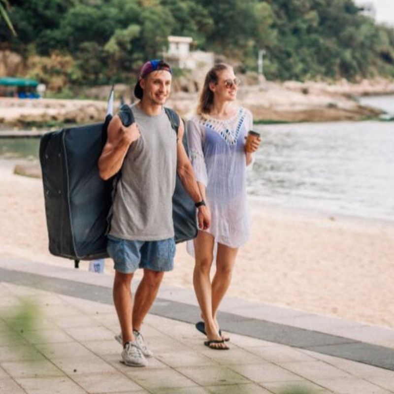 Couple walking along the beach carrying the Terravent K1 Folding Kayak in a case