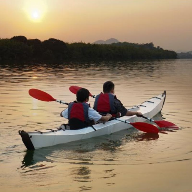 Family paddling in a Terravent K3 Folding Kayak on a scenic lake with blue skies